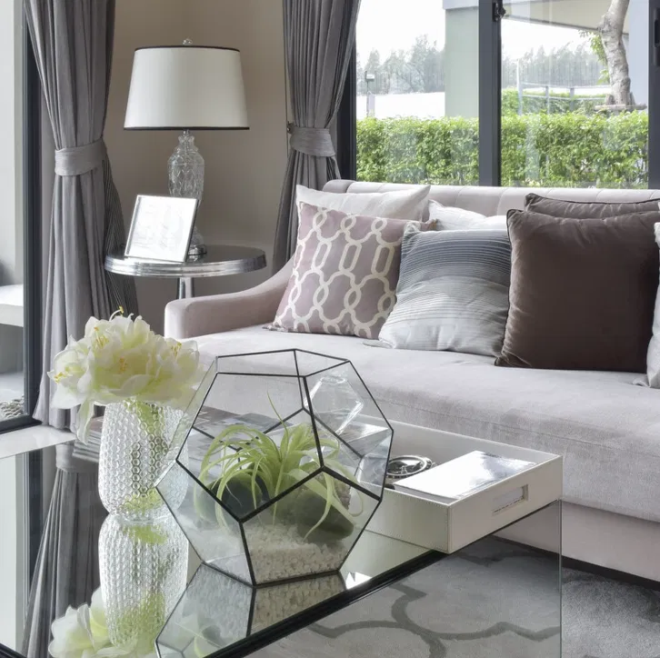 Table basse en verre avec terrarium et vase de fleurs, salon cocooning avec coussins